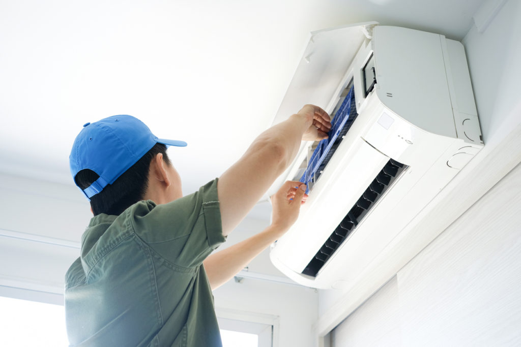 Male repair air conditioner at room, He is air conditioner technician in Winnipeg.